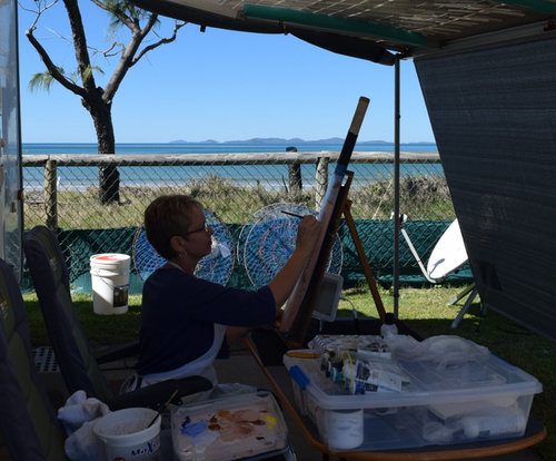 Artist Carole Elliott in her ‘Studio Under the Awning’ painting a cricket bat for charity. See her portfolio by visiting www.ArtsyShark.com.