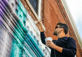 Gibbs Rounsavall at work on the "Sunshine and Shadow" mural. Uneven surfaces can pose challenges to the painter.