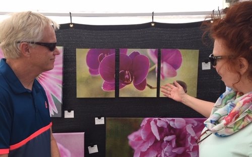 Photographer Kathleen Hall speaks with a visitor to her booth.