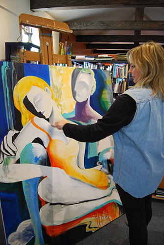 Artist Jeanette Jarville in her studio at work on one of her abstract figurative paintings