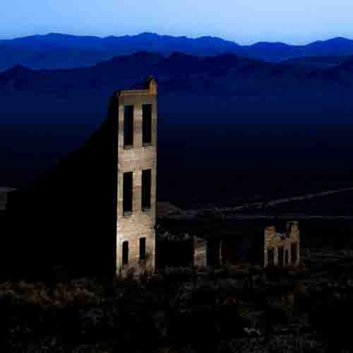 "Abandoned Dreams" Photograph of deteriorating buildings set against a mountain range by Steve Bennett