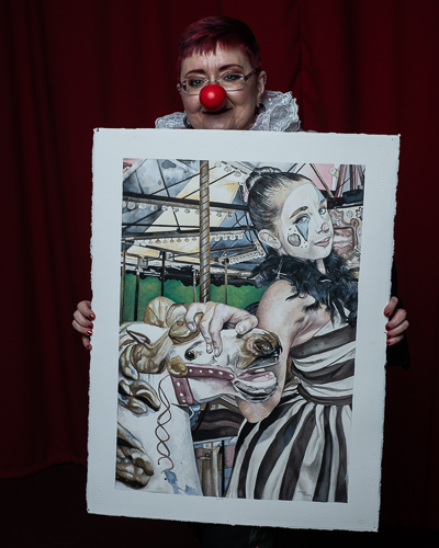 Artist DebiLynn Fendley in the studio holding her painting "Carousel"