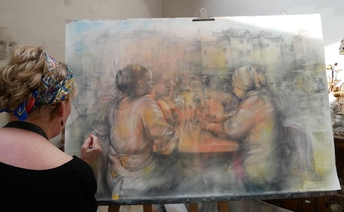 Artist Maggie Wrightat work in her studio on a large drawing of people at a table