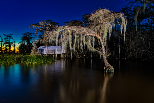 Photograph of an old tin fishing camp tucked in the trees on the edge of Louisiana's Lake Maurepas by Andy Crawford