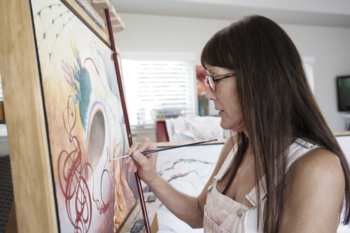 Artist Marjorie Darrow painting in her studio