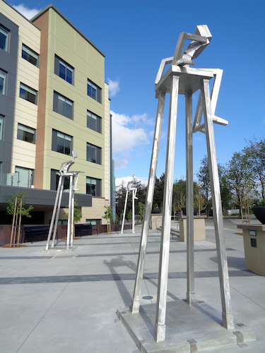 Abstract figurative aluminum sculptures of figures sitting in tall chairs by James Moore