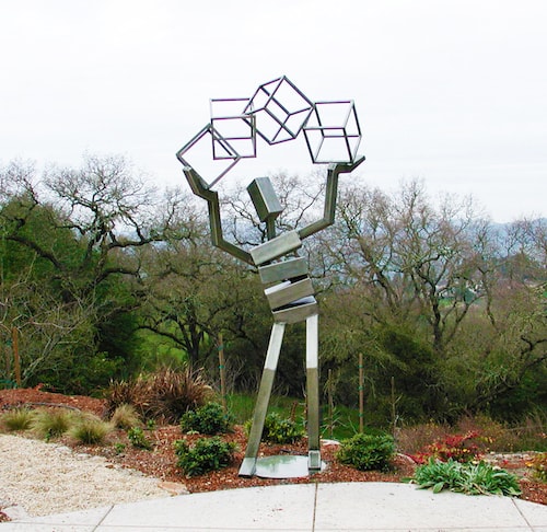 Abstract figurative stainless steel sculpture of a figure juggling shapes by James Moore