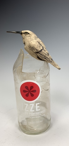 Stoneware and found object sculpture of a bird on a broken glass bottle by Deana Bada Maloney