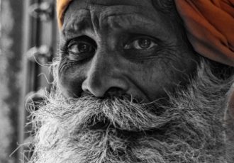 Black & white photograph with color of a doorman in India by Dave Maes