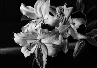 Black and White photograph of a sculpture of a female nude and flowers by Bonnie Kamhi