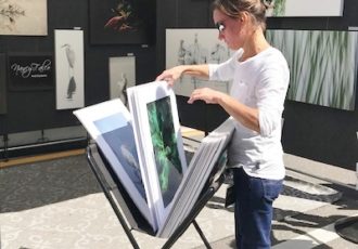 Customer looks at prints at an outdoor art fair