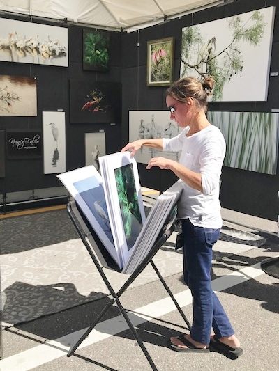 Customer looks at prints at an outdoor art fair