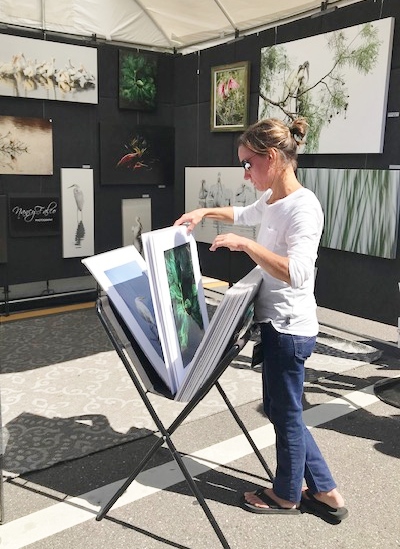 Customer looks at prints at an outdoor art fair