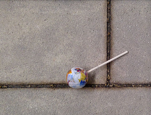 mixed media painting of a lollipop on pavers by Roberta Lynn Rose