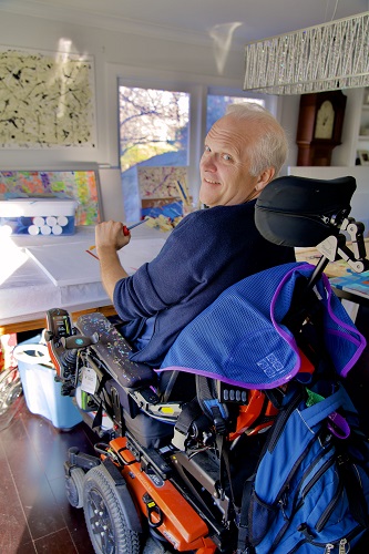 Teraplegic artist Alder Crocker paints using a special table in his studio