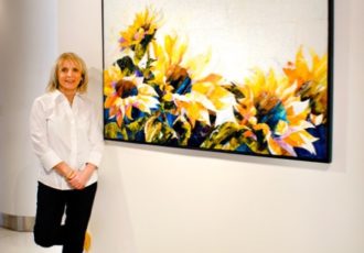 Artist Terri Albanese with a glass painting of sunflowers