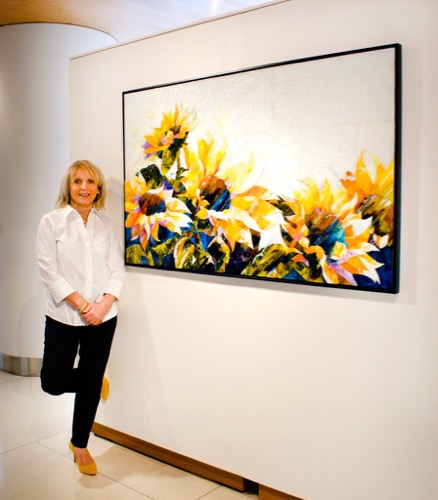 Artist Terri Albanese with a glass painting of sunflowers