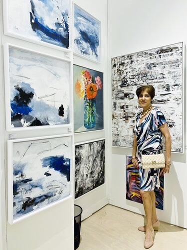 Artist Leila Pinto with her paintings at an exhibit