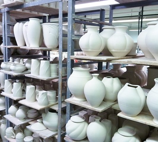 shelves of greenware in production pottery studio