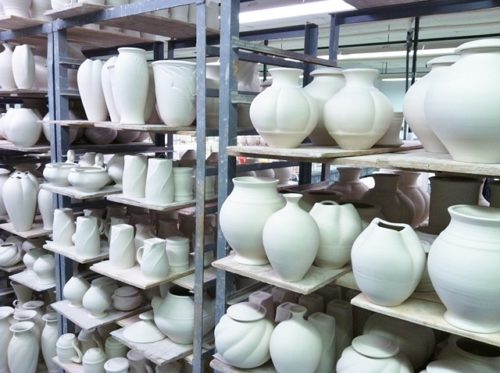 shelves of greenware in production pottery studio