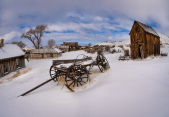 Photograph of an old wagon in snow in a Western ghost town