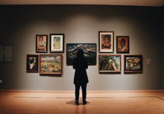 woman in black coat standing in front of paintings