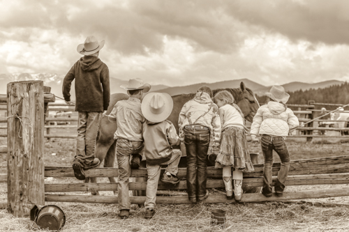 black and white photo of children on a fence